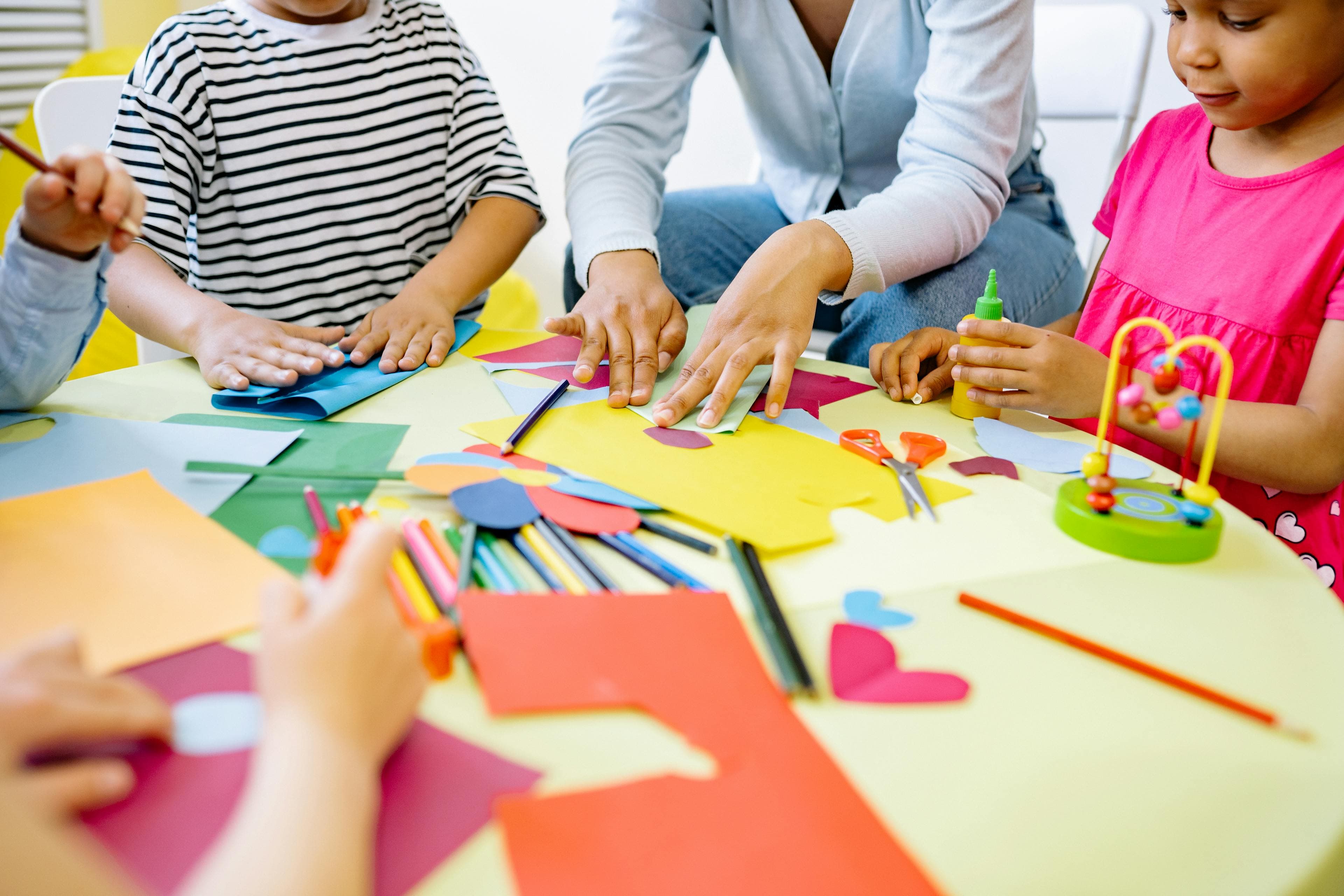 Children and teacher doing crafts together at a colorful table